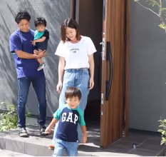 大きな取手のある玄関から出かける家族